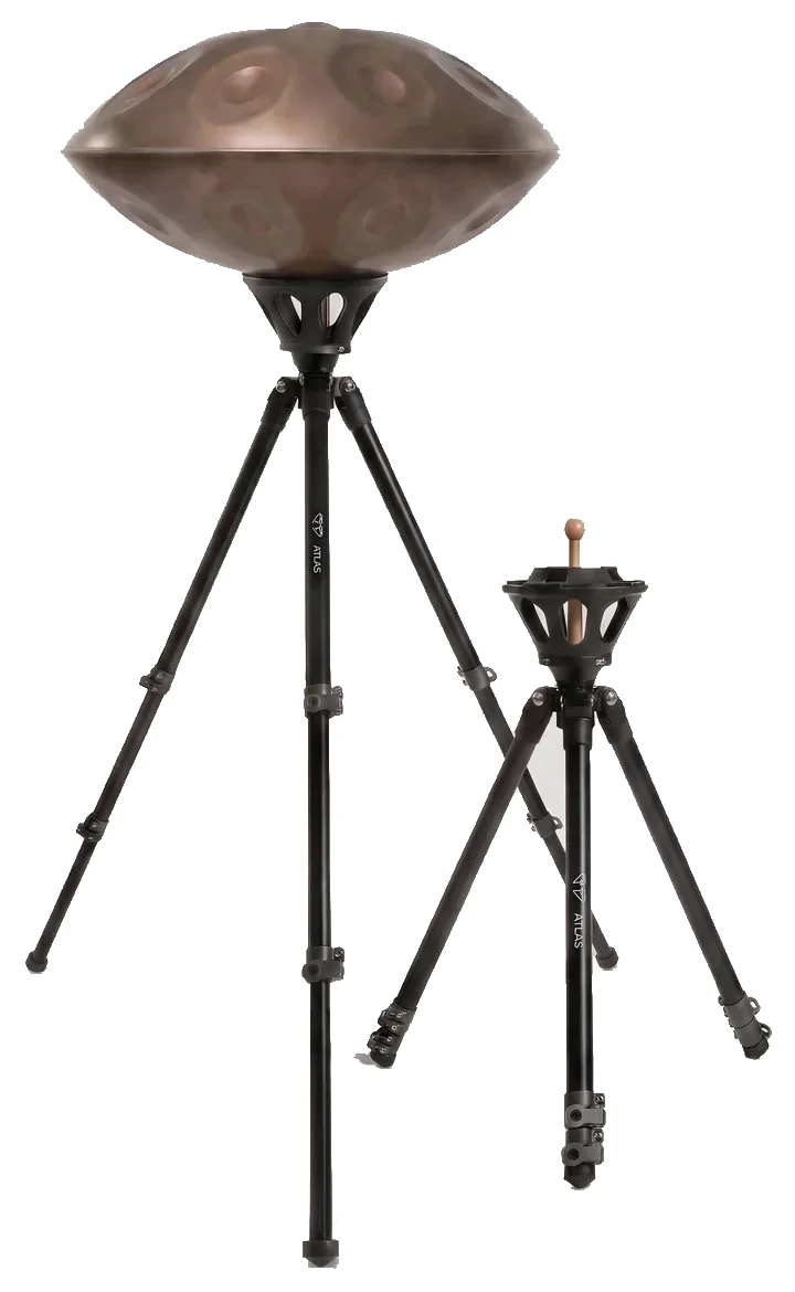Deux trépieds Atlas Pro côte à côte sur fond gris : celui de gauche est déployé en position haute et porte un handpan en acier, celui de droite est réglé en position basse, pieds resserrés.