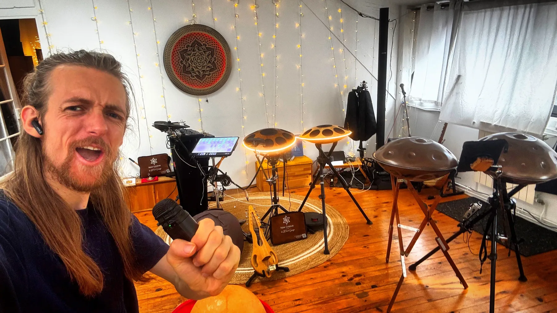 David Lesage, micro en main, présente les instruments du showroom : les Neotone et les handpans Yishama alignés derrière lui, sous la rosace du mur.